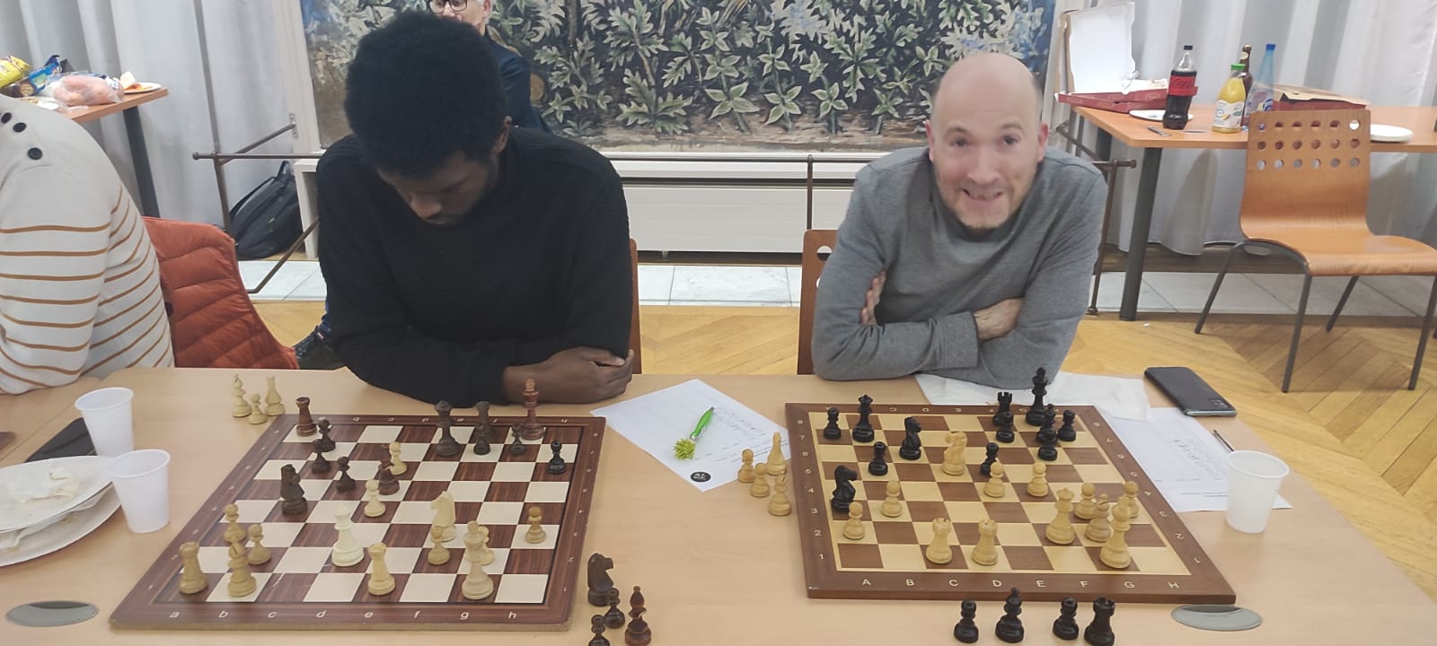 Deux joueurs concentrés sur leurs échiquiers au club